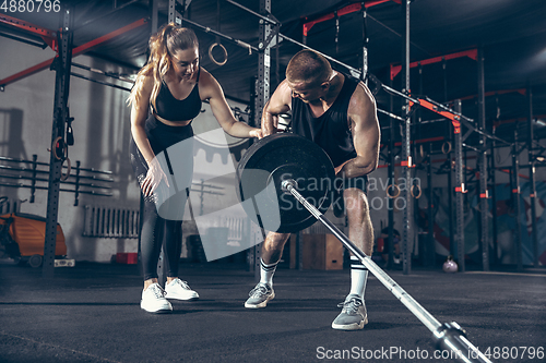 Image of Beautiful young sporty couple training, workout in gym together
