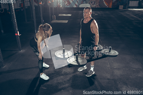 Image of Beautiful young sporty couple training, workout in gym together