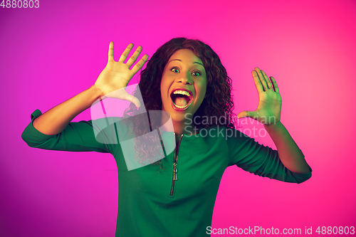 Image of African-american young woman\'s portrait isolated on gradient pink background in neon light