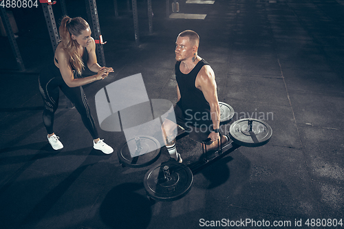 Image of Beautiful young sporty couple training, workout in gym together