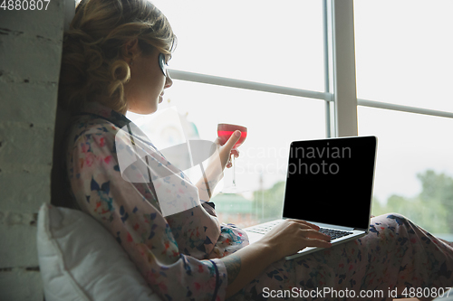 Image of Portrait of pretty young girl in modern apartment in the morning. Resting, calm, salisfied. Youth and wellness concept.