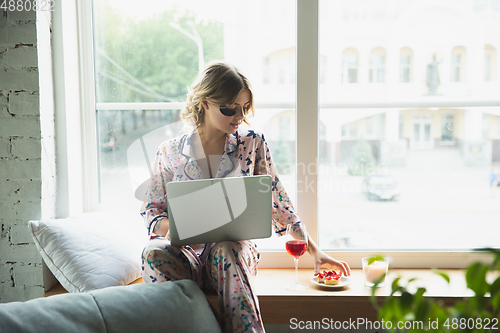 Image of Portrait of pretty young girl in modern apartment in the morning. Resting, calm, salisfied. Youth and wellness concept.