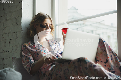 Image of Portrait of pretty young girl in modern apartment in the morning. Resting, calm, salisfied. Youth and wellness concept.