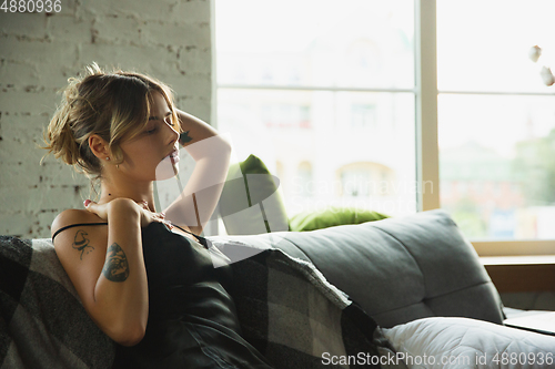 Image of Portrait of pretty young girl in modern apartment in the morning. Resting, calm, salisfied. Youth and wellness concept.