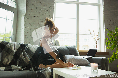 Image of Portrait of pretty young girl in modern apartment in the morning. Resting, calm, salisfied. Youth and wellness concept.