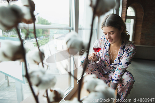 Image of Portrait of pretty young girl in modern apartment in the morning. Resting, calm, salisfied. Youth and wellness concept.