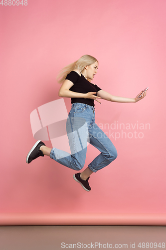 Image of Portrait of young caucasian woman with bright emotions on coral pink studio background