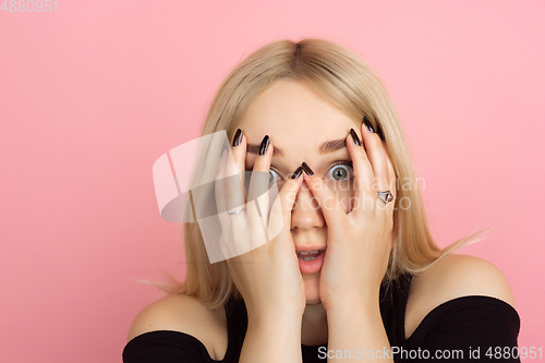 Image of Portrait of young caucasian woman with bright emotions on coral pink studio background