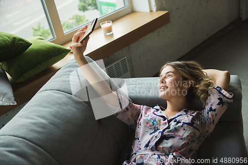 Image of Portrait of pretty young girl in modern apartment in the morning. Resting, calm, salisfied. Youth and wellness concept.