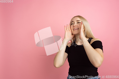 Image of Portrait of young caucasian woman with bright emotions on coral pink studio background