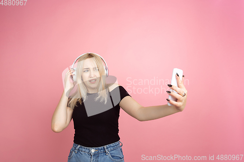 Image of Portrait of young caucasian woman with bright emotions on coral pink studio background