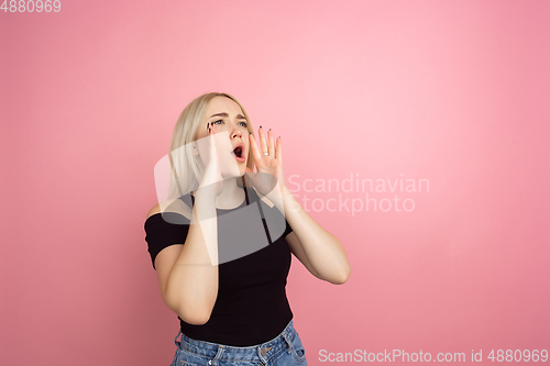 Image of Portrait of young caucasian woman with bright emotions on coral pink studio background