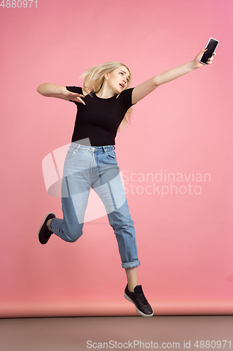 Image of Portrait of young caucasian woman with bright emotions on coral pink studio background