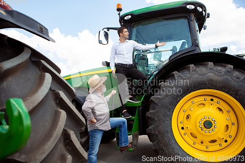 Image of A farmer with a tractor, combine at a field in sunlight. Confident, bright colors