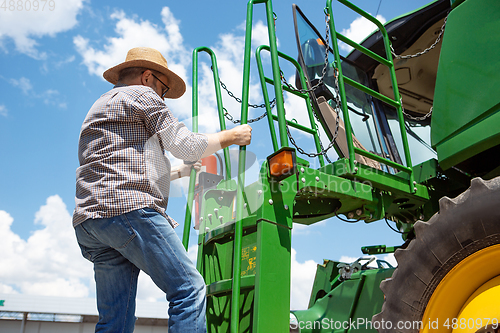 Image of A farmer with a tractor, combine at a field in sunlight. Confident, bright colors