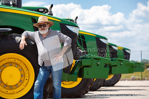 Image of A farmer with a tractor, combine at a field in sunlight. Confident, bright colors