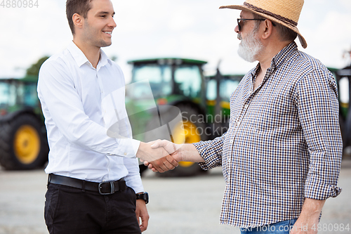 Image of A farmer with a tractor, combine at a field in sunlight. Confident, bright colors