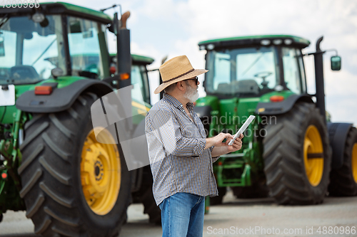 Image of A farmer with a tractor, combine at a field in sunlight. Confident, bright colors