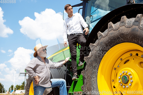 Image of A farmer with a tractor, combine at a field in sunlight. Confident, bright colors