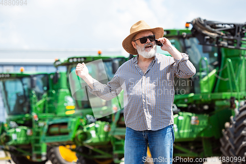 Image of A farmer with a tractor, combine at a field in sunlight. Confident, bright colors