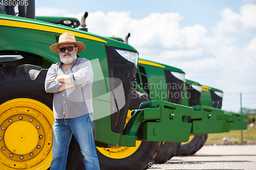 Image of A farmer with a tractor, combine at a field in sunlight. Confident, bright colors