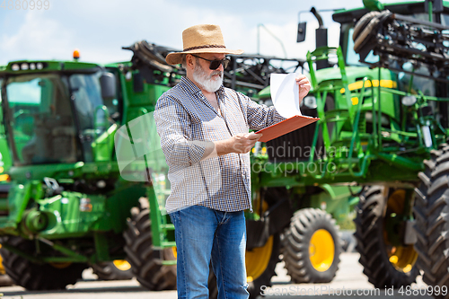 Image of A farmer with a tractor, combine at a field in sunlight. Confident, bright colors