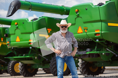 Image of A farmer with a tractor, combine at a field in sunlight. Confident, bright colors