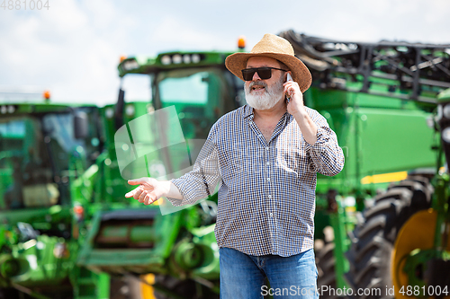 Image of A farmer with a tractor, combine at a field in sunlight. Confident, bright colors