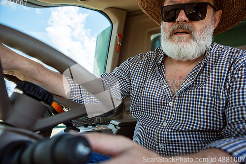 Image of A farmer with a tractor, combine at a field in sunlight. Confident, bright colors