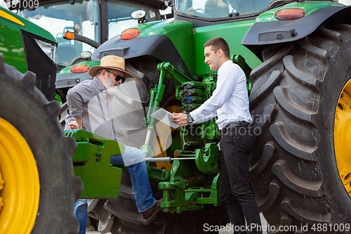 Image of A farmer with a tractor, combine at a field in sunlight. Confident, bright colors