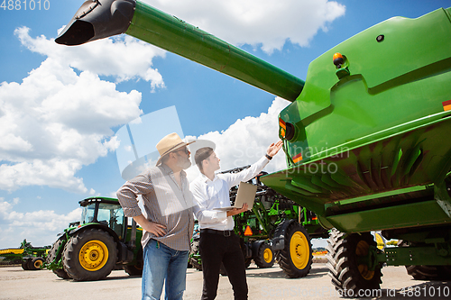 Image of A farmer with a tractor, combine at a field in sunlight. Confident, bright colors