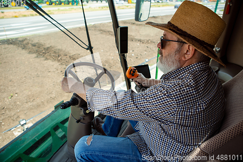 Image of A farmer with a tractor, combine at a field in sunlight. Confident, bright colors