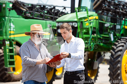 Image of A farmer with a tractor, combine at a field in sunlight. Confident, bright colors