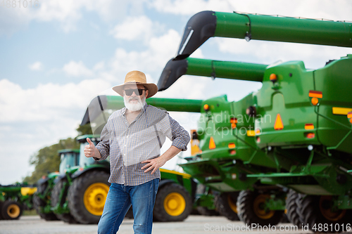 Image of A farmer with a tractor, combine at a field in sunlight. Confident, bright colors