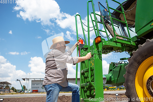 Image of A farmer with a tractor, combine at a field in sunlight. Confident, bright colors