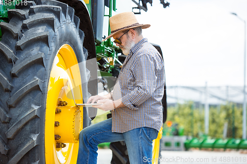 Image of A farmer with a tractor, combine at a field in sunlight. Confident, bright colors