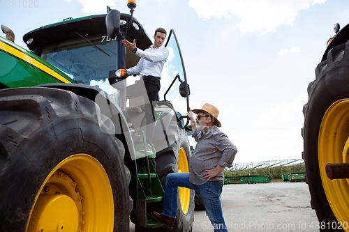 Image of A farmer with a tractor, combine at a field in sunlight. Confident, bright colors