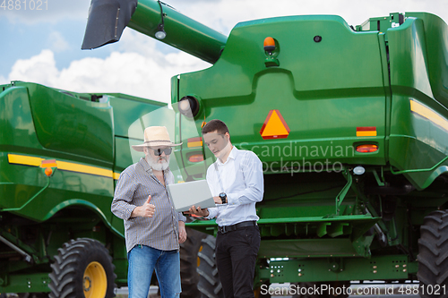 Image of A farmer with a tractor, combine at a field in sunlight. Confident, bright colors