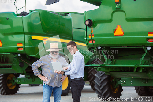 Image of A farmer with a tractor, combine at a field in sunlight. Confident, bright colors