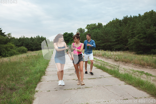 Image of Group of friends clinking beer bottles during picnic in summer forest. Lifestyle, friendship