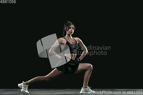 Image of Beautiful young female athlete practicing on black studio background, full length portrait