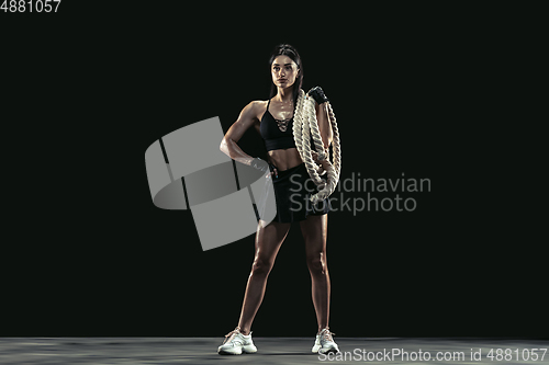 Image of Beautiful young female athlete practicing on black studio background, full length portrait