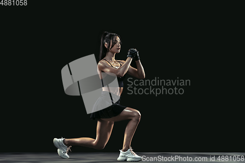 Image of Beautiful young female athlete practicing on black studio background, full length portrait
