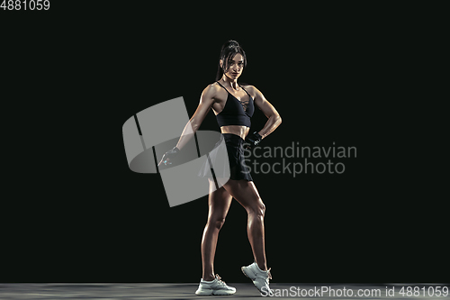 Image of Beautiful young female athlete practicing on black studio background, full length portrait