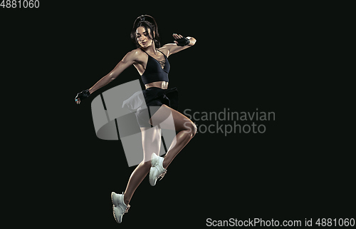 Image of Beautiful young female athlete practicing on black studio background, full length portrait