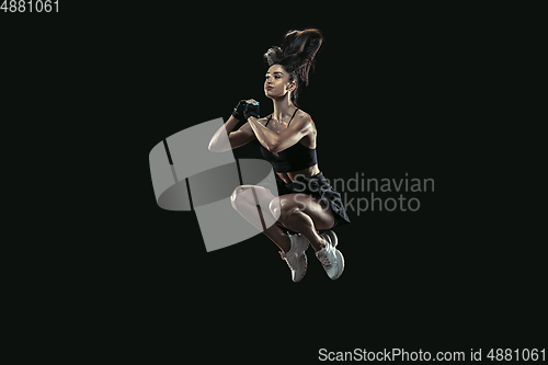 Image of Beautiful young female athlete practicing on black studio background, full length portrait