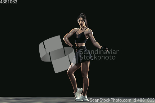 Image of Beautiful young female athlete practicing on black studio background, full length portrait