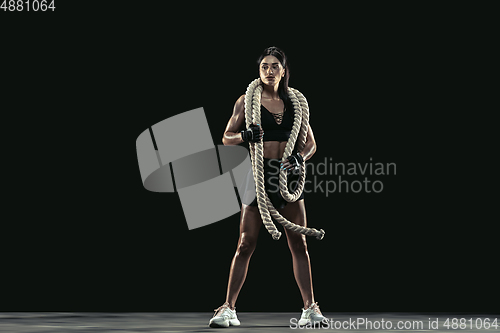 Image of Beautiful young female athlete practicing on black studio background, full length portrait