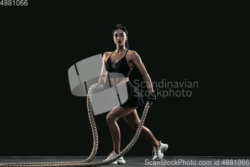 Image of Beautiful young female athlete practicing on black studio background, full length portrait