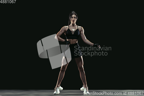 Image of Beautiful young female athlete practicing on black studio background, full length portrait